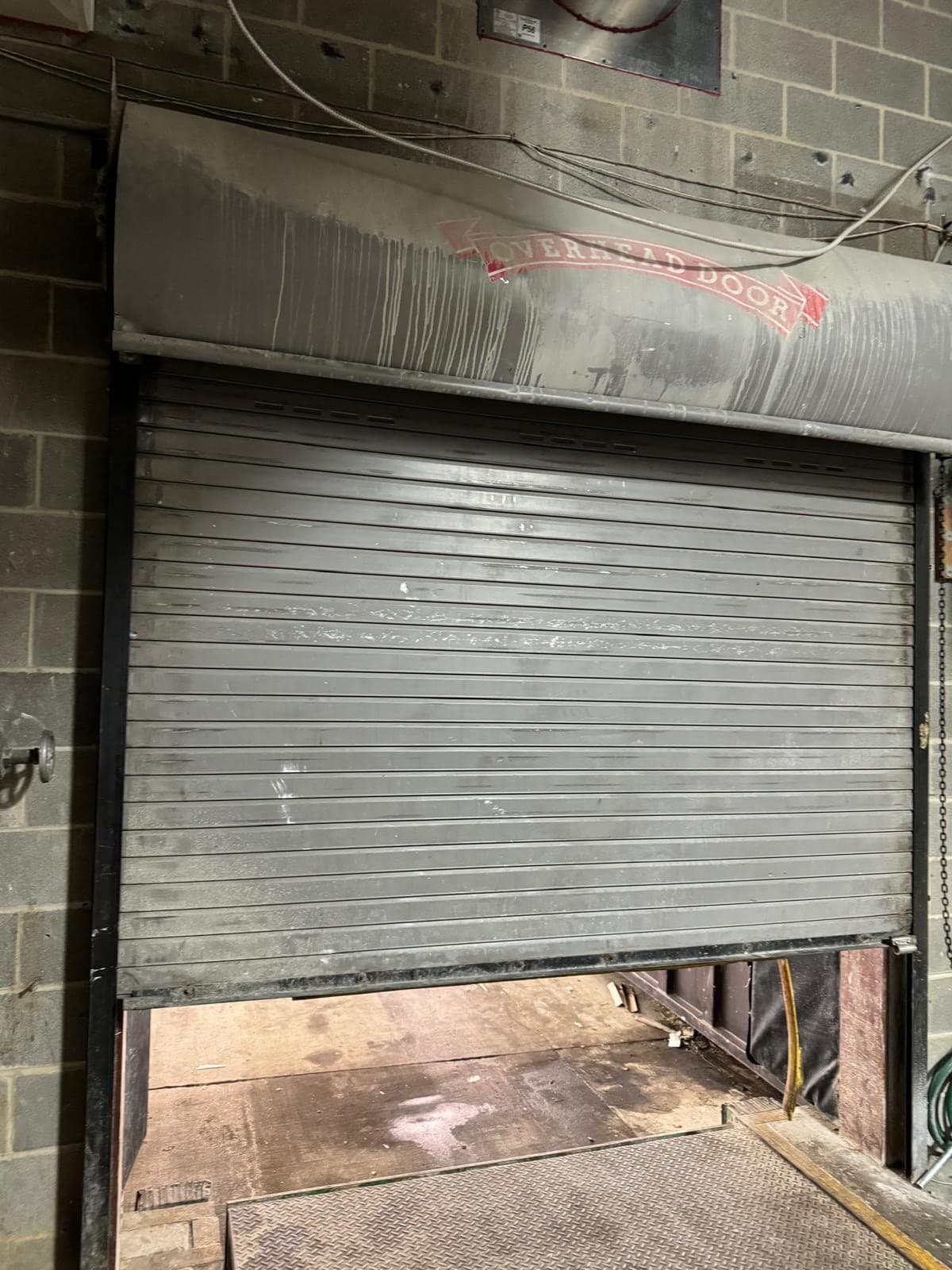 A grey rolling steel service door in a concrete-block wall, seen from inside a commercial building