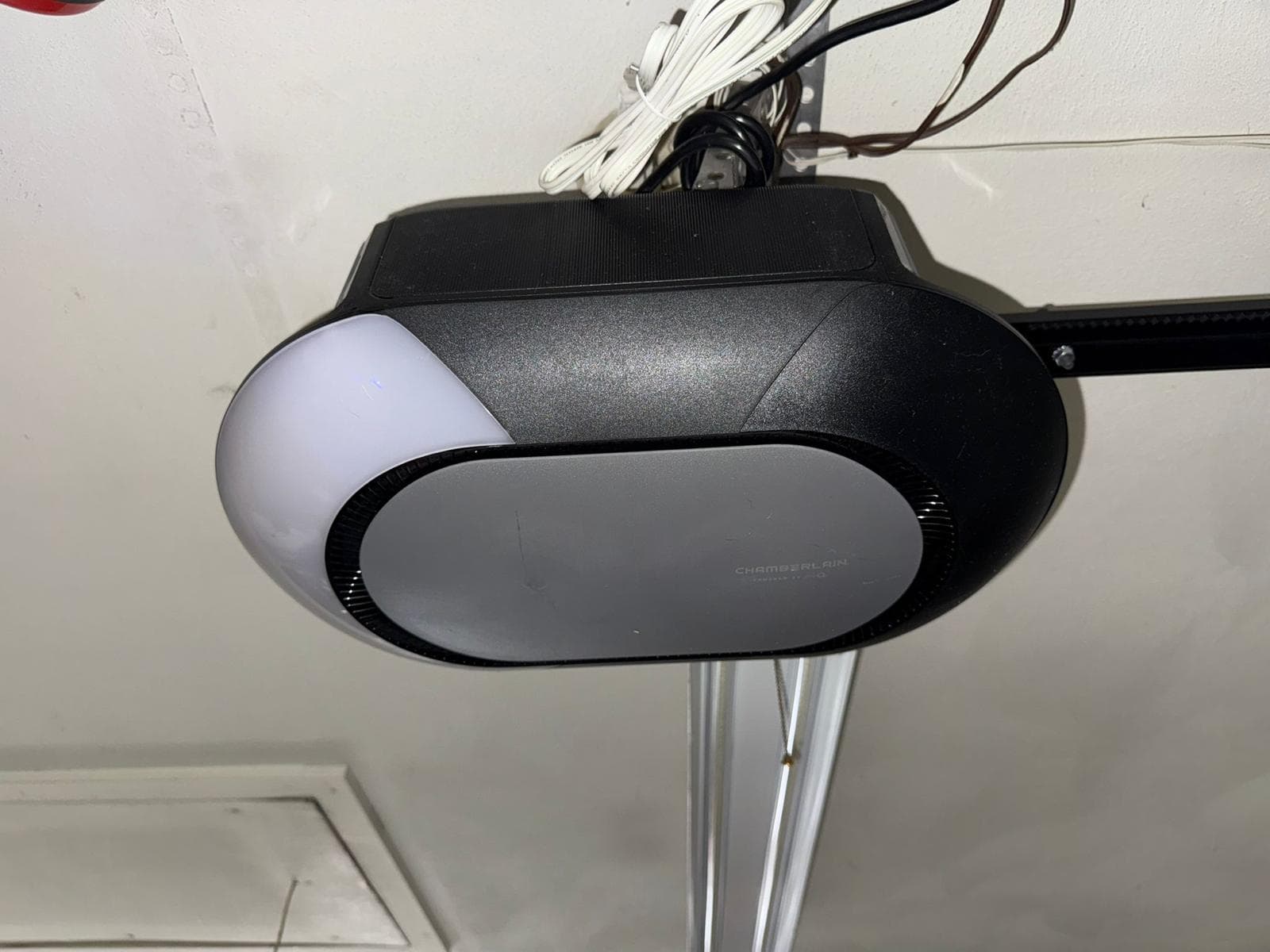 A Chamberlain belt-drive garage door opener mounted to the ceiling of a garage, with the rail and trolley visible